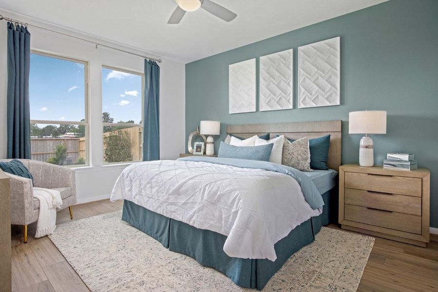 Come and unwind after a long day in this magnificent primary suite! This spacious room features plush carpet flooring, neutral paint, custom painted feature wall, high ceilings with ceiling fan, and large windows.