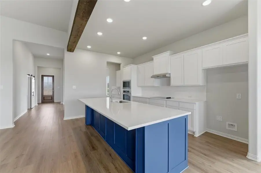The kitchen features a spacious island with a blue base and white countertop, white cabinetry, and recessed lighting