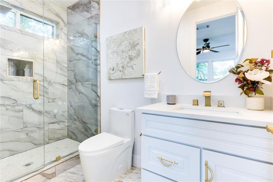 Bathroom featuring an enclosed shower, vanity, toilet, and a healthy amount of sunlight