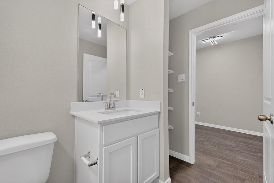 Clean lines and stone counters define this modern bathroom space featuring durable wood flooring.
