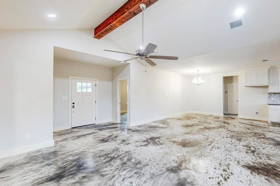 Unfurnished living room with lofted ceiling with beams and ceiling fan with notable chandelier