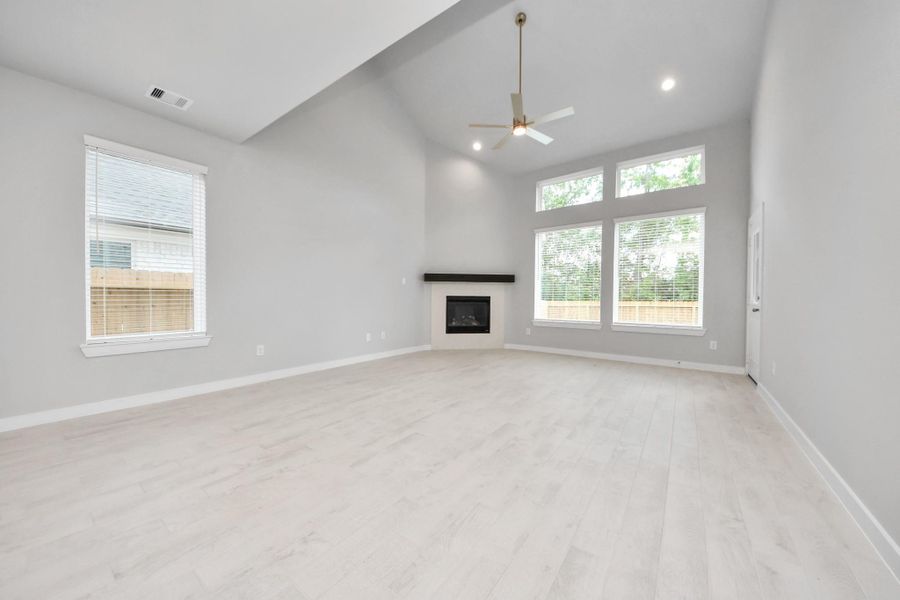 Relax and unwind in this inviting family room, illuminated by abundant natural light streaming in through tall windows, complemented by high ceilings and stunning flooring. Stay comfortable year-round with the gentle breeze from the ceiling fan, creating the perfect atmosphere for family gatherings.