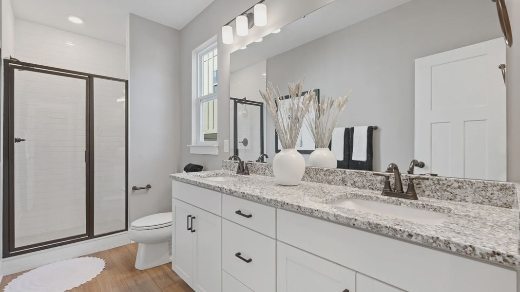 Notable primary bath featuring dual vanity, walk-in shower, and tasteful design touches throughout