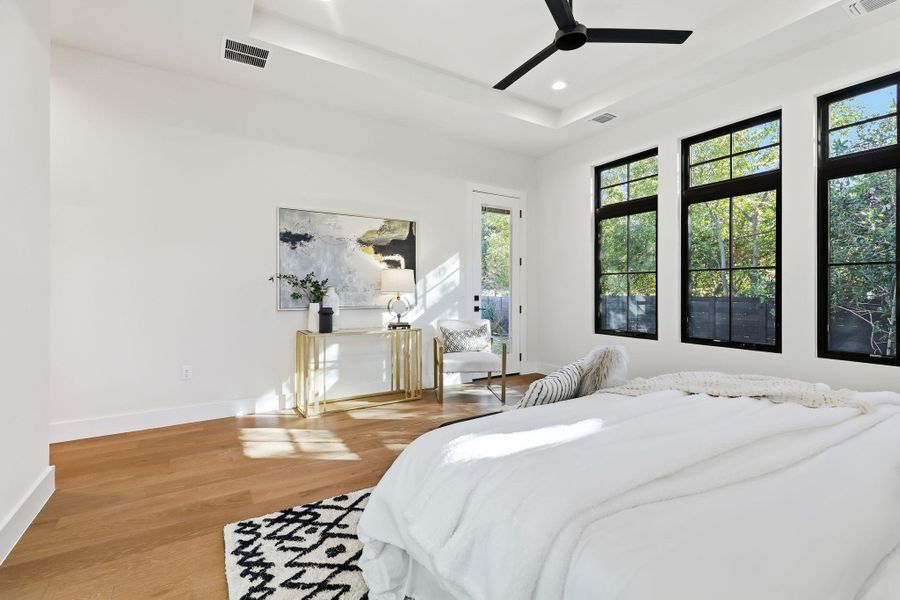 Bedroom featuring light wood finished floors, a ceiling fan, access to outside, a tray ceiling, and recessed lighting