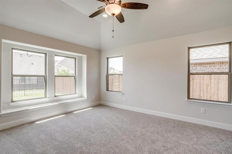 Carpeted empty room featuring high vaulted ceiling and ceiling fan