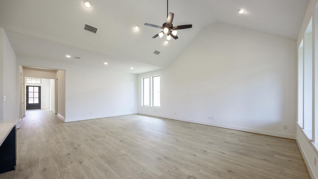Spare room with high vaulted ceiling, light wood-type flooring, recessed lighting, and a ceiling fan Spare room with high vaulted ceiling, light wood-type flooring, recessed lighting, and a ceiling fan