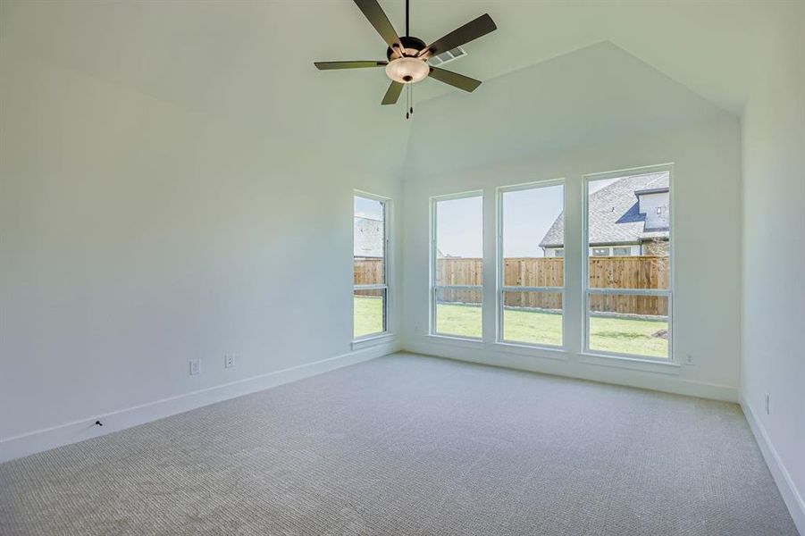Empty room with carpet, ceiling fan, and high vaulted ceiling
