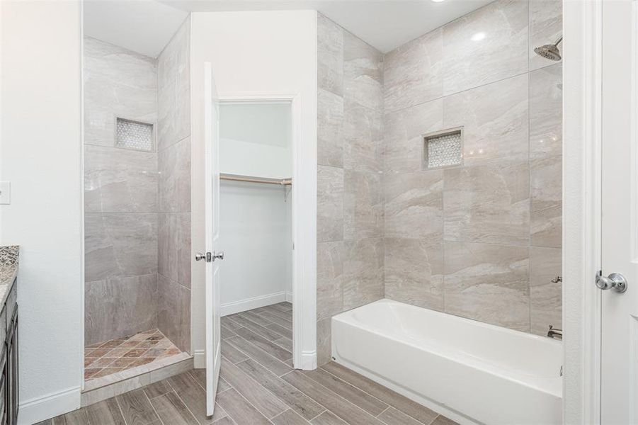 Bathroom with wood finish floors, a walk in closet, and baseboards