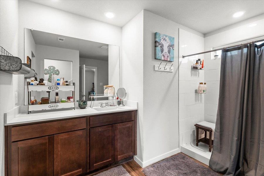 Full bathroom with vanity, a stall shower, dark wood-style flooring, and recessed lighting
