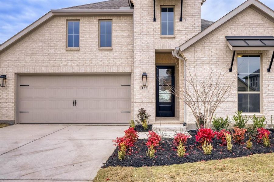 View of front of house with roof with shingles, driveway, and brick siding