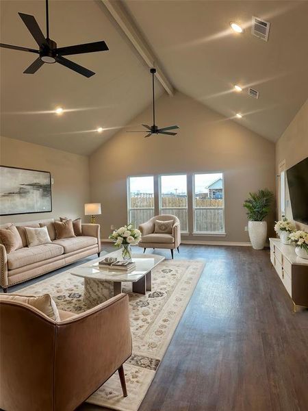 Living room featuring ceiling fan, dark wood-type flooring, high vaulted ceiling, and beamed ceiling