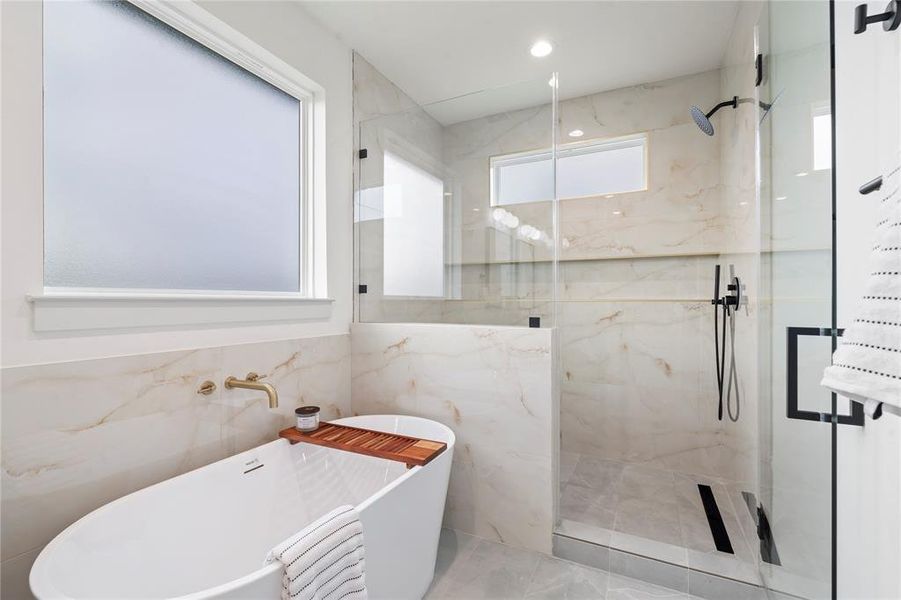 The primary bathroom is a true spa retreat, featuring a luxurious freestanding soaking tub and an expansive walk-in shower designed for both relaxation and functionality.