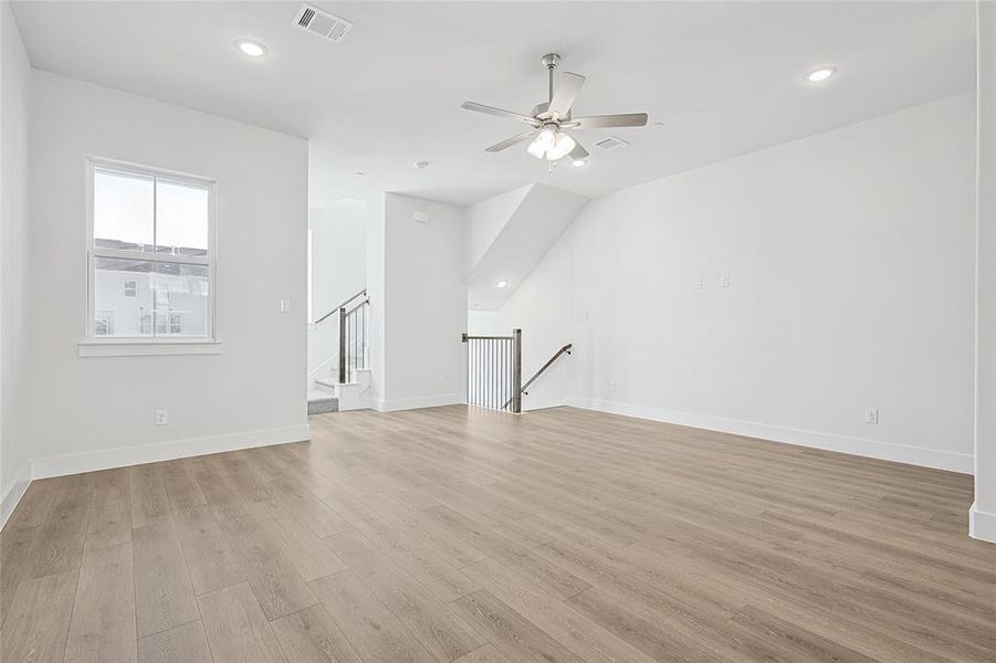 This spacious interior features light wood-look flooring, white walls, and recessed lighting