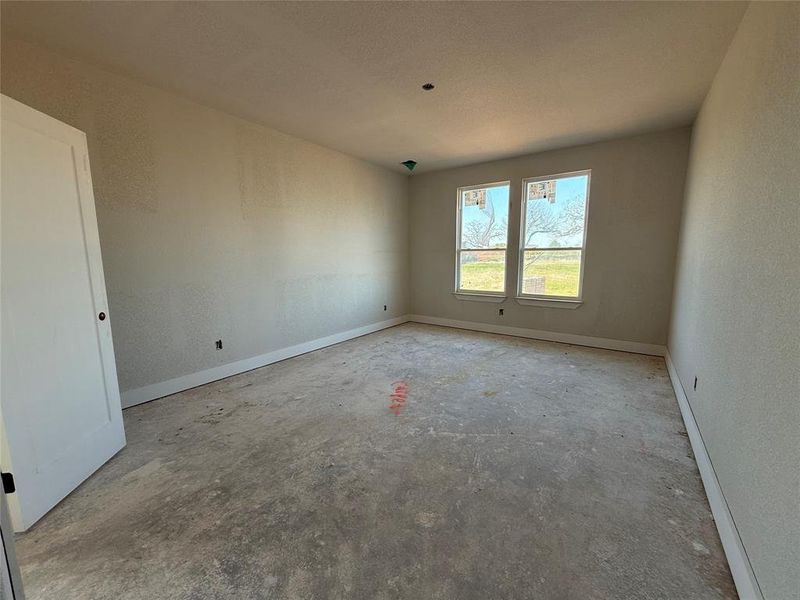 Spare room with unfinished concrete flooring, a textured wall, and baseboards