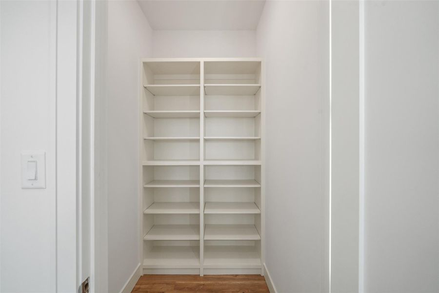 Well-lit hall storage space with built-in white shelving, ideal for organizing items. Wood floor adds warmth to the clean, modern design.