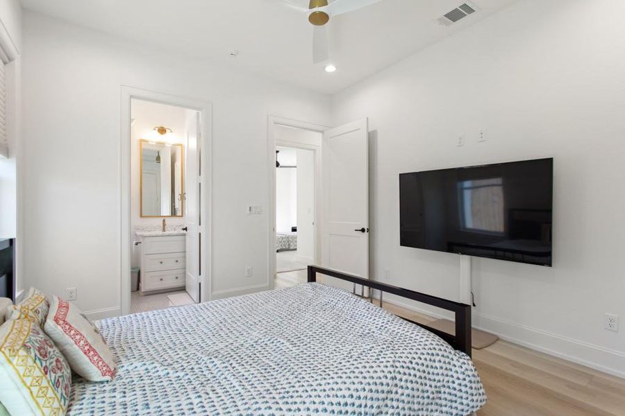 Bedroom with light wood-type flooring, recessed lighting, ensuite bathroom, and a ceiling fan