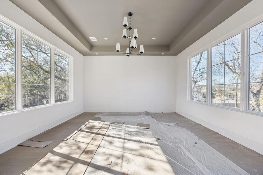 Primary Bedroom with a Coffered Ceiling.  There are windows on each side of the room.