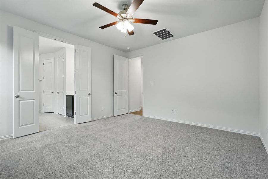Unfurnished bedroom with light carpet, baseboards, and ceiling fan Unfurnished bedroom with light carpet, baseboards, and ceiling fan