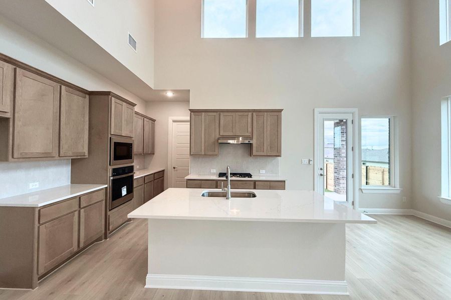 A spacious, airy kitchen features high ceilings, a grand island, and abundant natural light. A spacious, airy kitchen features high ceilings, a grand island, and abundant natural light.
