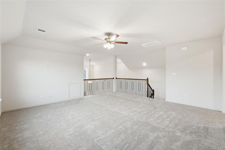 Empty room with vaulted ceiling, light colored carpet, and ceiling fan