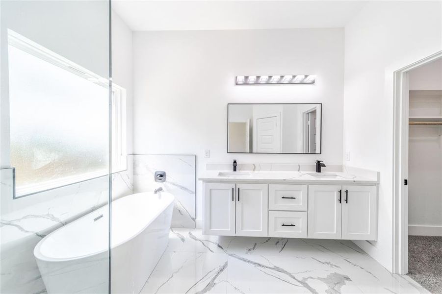 Full bathroom featuring a freestanding tub, double vanity, and a spacious closet