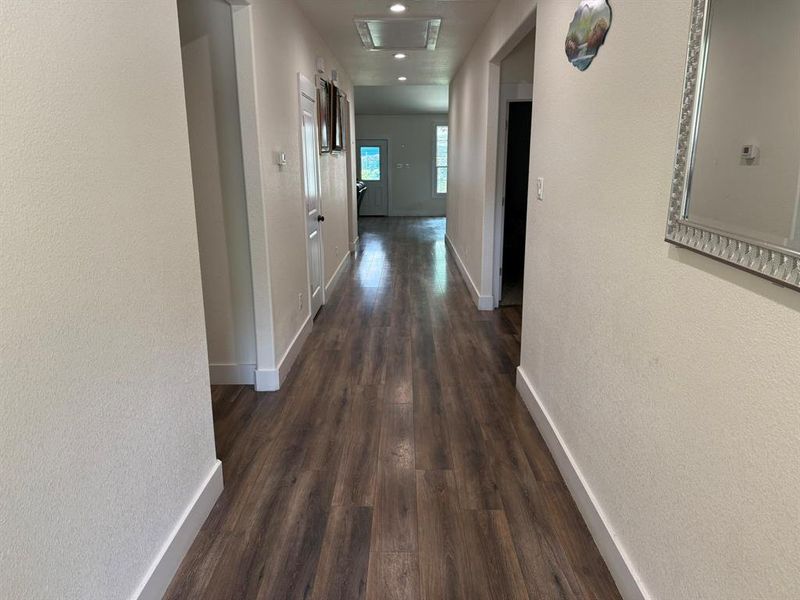 Corridor with dark wood-type flooring and a textured wall