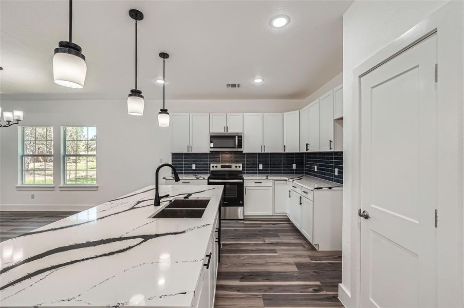 Kitchen featuring stainless steel appliances, recessed lighting, backsplash, and white cabinets