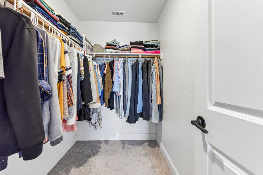 A well-organized walk-in closet offers abundant hanging space and convenient upper shelving.