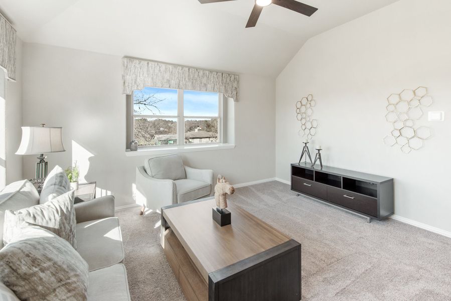 Living room with vaulted ceiling, ceiling fan, gray seating, wood coffee table, and carpet flooring