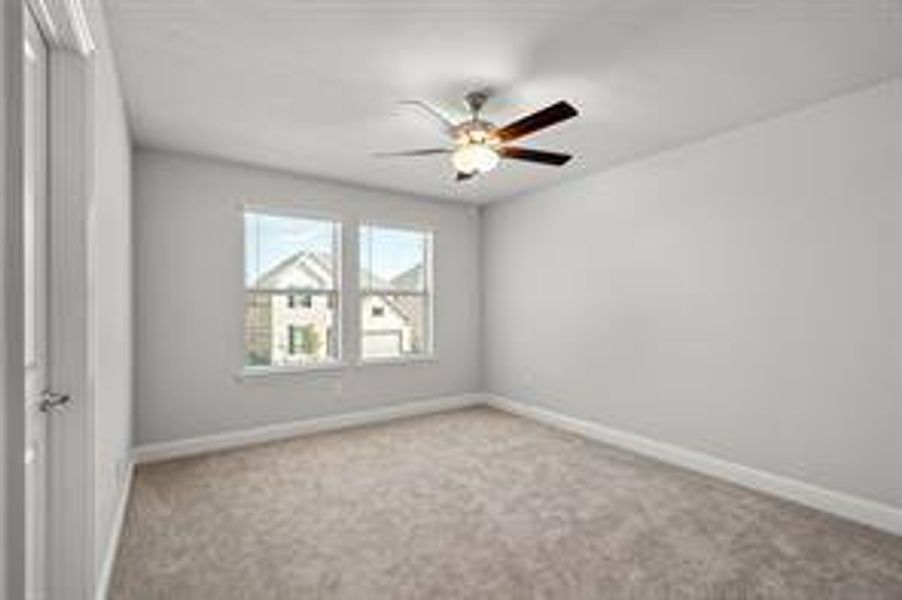 Carpeted spare room featuring ceiling fan