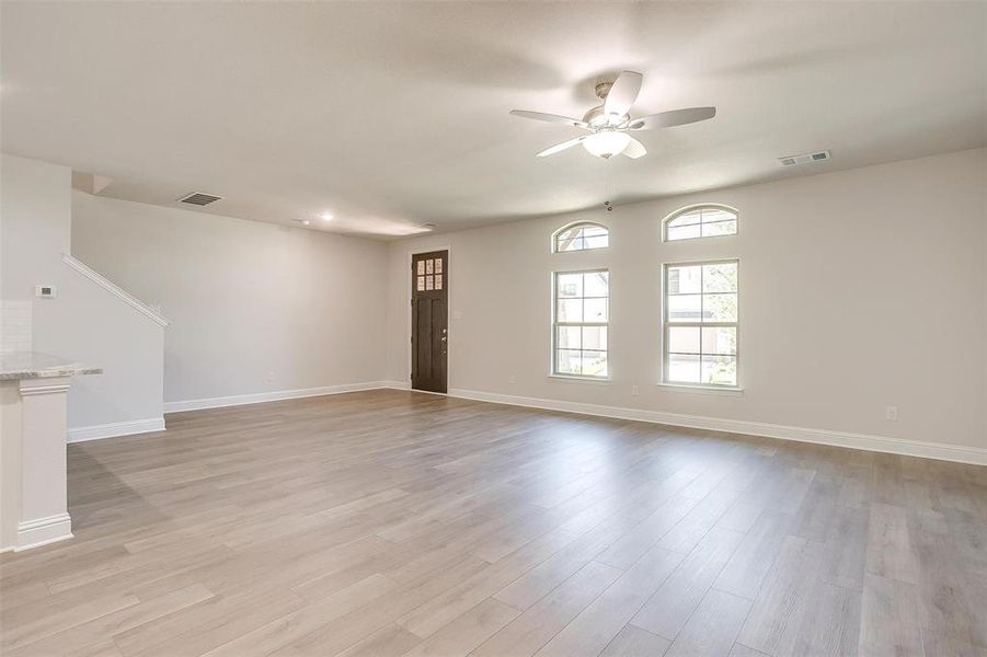 Unfurnished living room featuring light wood finished floors and ceiling fan Unfurnished living room featuring light wood finished floors and ceiling fan