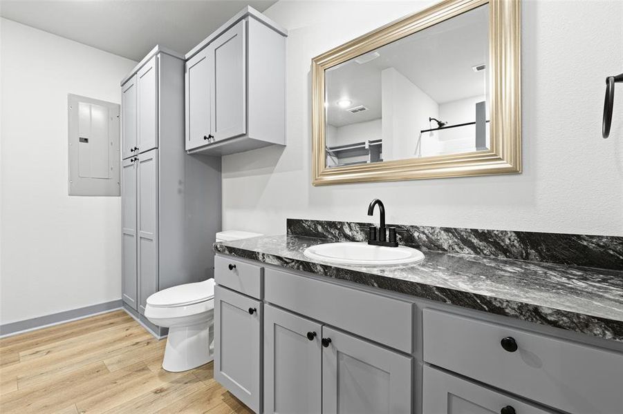 Bathroom featuring light wood-style floors, vanity, electric panel, and a closet Bathroom featuring light wood-style floors, vanity, electric panel, and a closet