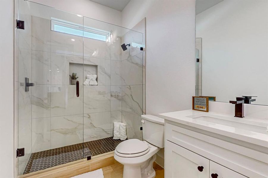 Hall Bathroom featuring a shower with door, tile flooring, vanity, and toilet