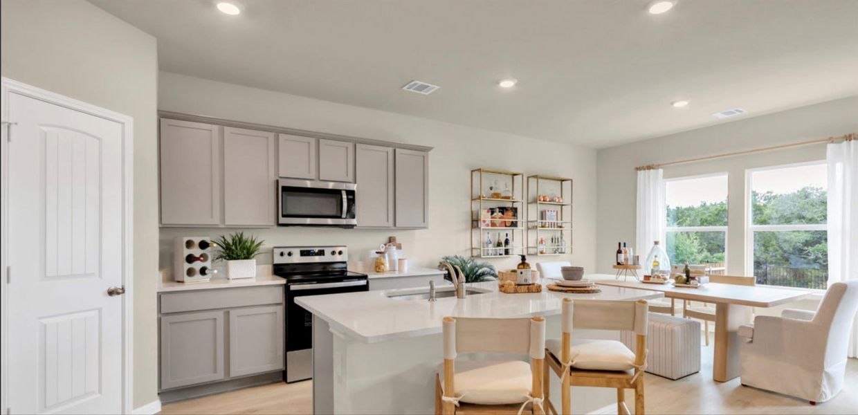 Kitchen with gray cabinets, stainless steel appliances, recessed lighting, a kitchen island with sink, and light stone counters