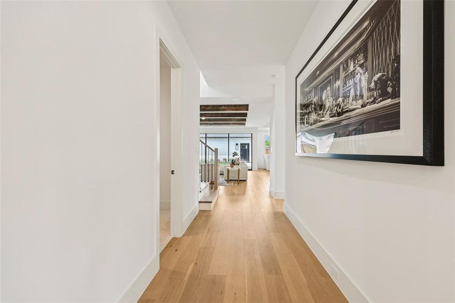 Hallway featuring light wood-finish flooring and crisp white walls
