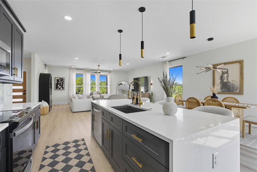 Kitchen featuring ceiling fan, open floor plan, decorative light fixtures, light wood-style floors, and light stone counters