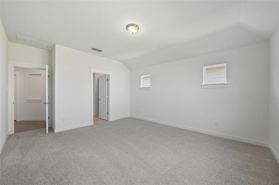 Unfurnished bedroom featuring light carpet and vaulted ceiling