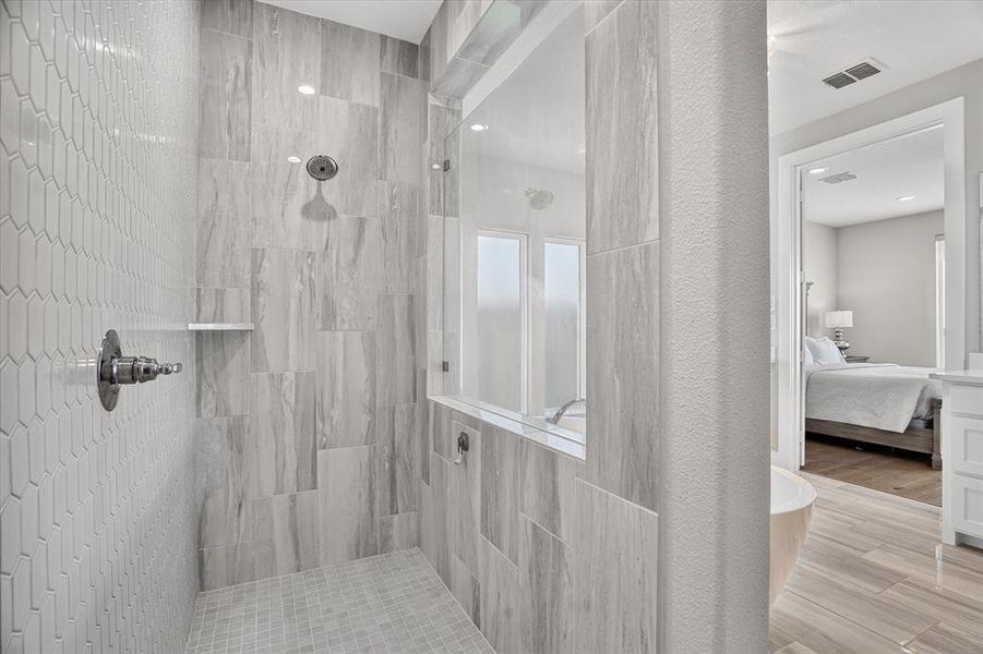 Spacious shower featuring floor-to-ceiling tile, a built-in shelf, and a rainfall showerhead Spacious shower featuring floor-to-ceiling tile, a built-in shelf, and a rainfall showerhead