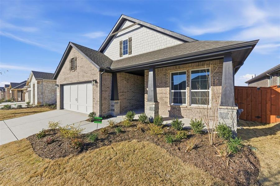 View of front of property with roof with shingles, brick siding, covered porch, concrete driveway, and a garage