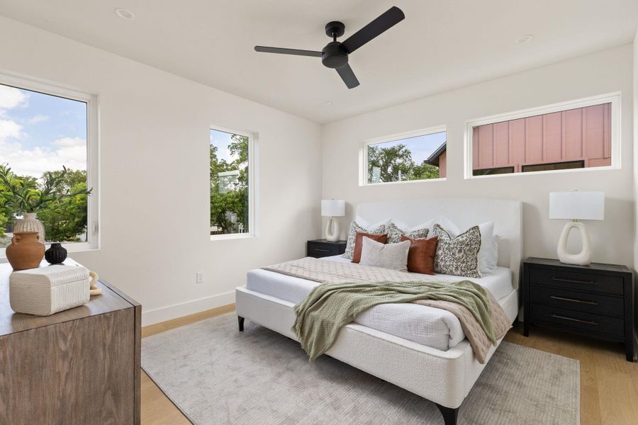 Natural light floods this generously sized bedroom, featuring warm hardwood floors and ample windows. Natural light floods this generously sized bedroom, featuring warm hardwood floors and ample windows.