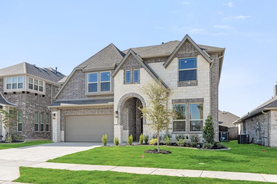 Two-story home with brick and stone exterior, arched entry, two-car garage, and manicured front lawn Two-story home with brick and stone exterior, arched entry, two-car garage, and manicured front lawn