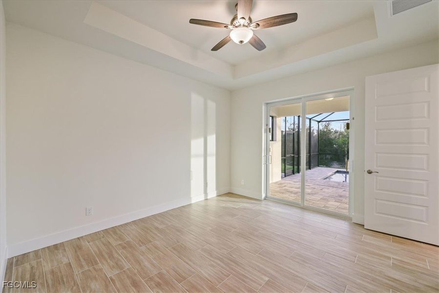 Unfurnished room with a ceiling fan, wood finish floors, and a tray ceiling