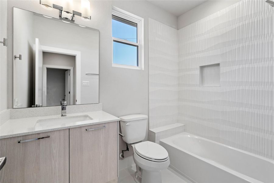 Modern full bath shared by the secondary bedrooms, featuring a floating vanity, large framed mirror & sleek tile surround for a bright, contemporary feel. Modern full bath shared by the secondary bedrooms, featuring a floating vanity, large framed mirror & sleek tile surround for a bright, contemporary feel.