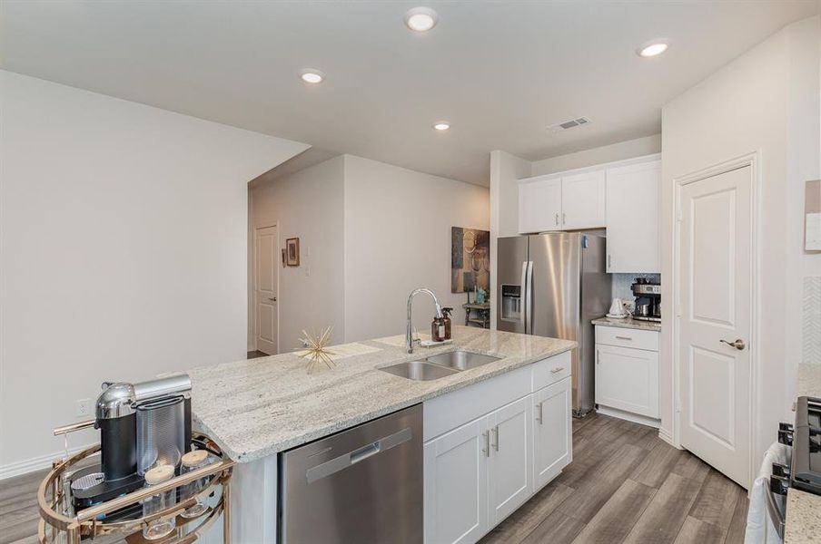 Kitchen featuring light stone counters, white cabinets, stainless steel appliances, light hardwood / wood-style flooring, and sink