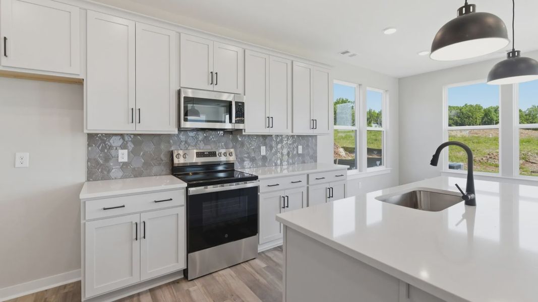 Kitchen with tile backsplash, pendant lighting, and quartz countertops