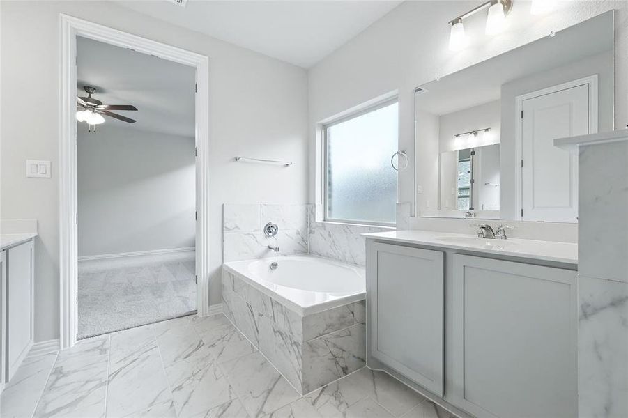 Full bathroom featuring vanity, a bath, marble finish floors, and a ceiling fan Full bathroom featuring vanity, a bath, marble finish floors, and a ceiling fan