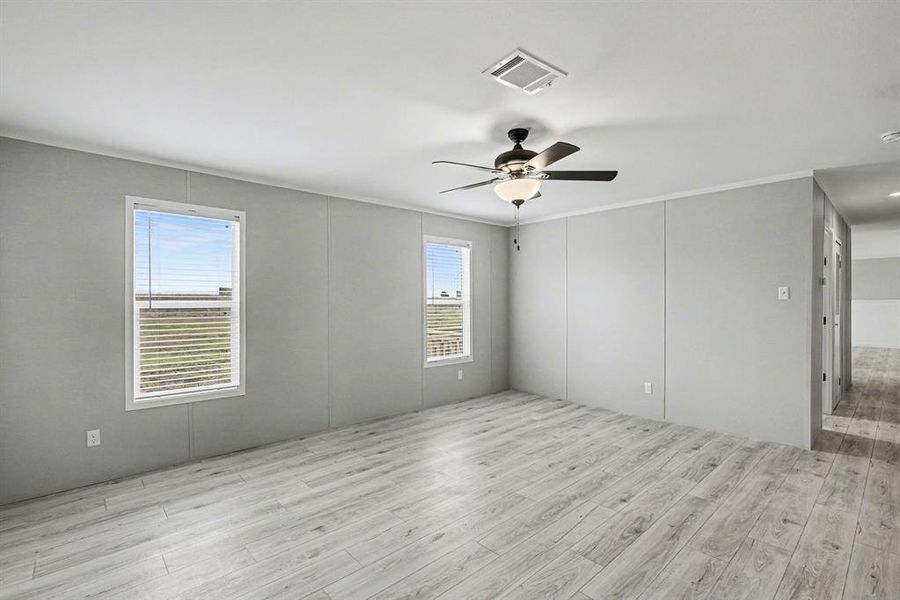 Spacious flex-room featuring wood-look flooring, a ceiling fan with light, light grey walls, and two windows.  Will this be an additional living space? Office? Play area? Media room? - so many options