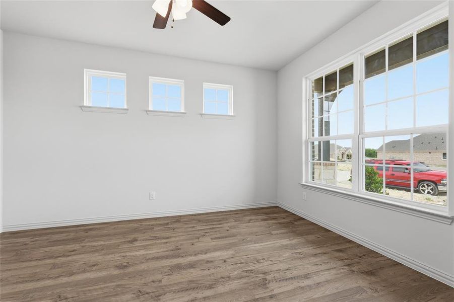 Spacious room featuring wood-finish flooring, white baseboards, and bright white walls