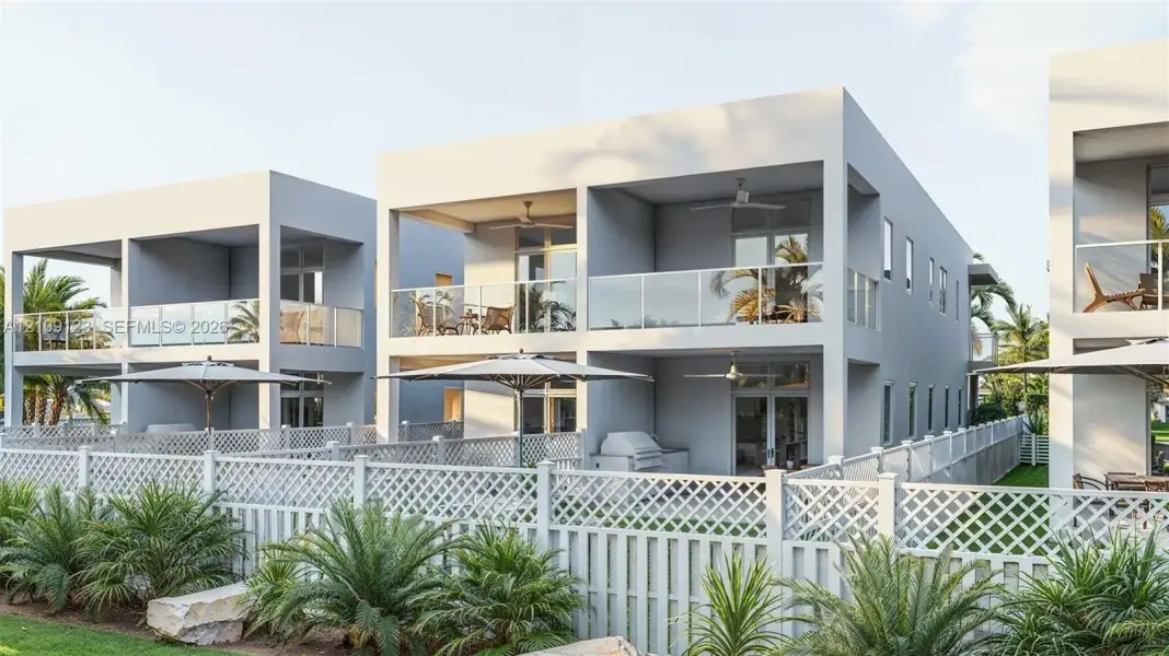Contemporary multi-level structures featuring private covered balconies with glass railings, built-in outdoor kitchen components, and white lattice fencing Contemporary multi-level structures featuring private covered balconies with glass railings, built-in outdoor kitchen components, and white lattice fencing