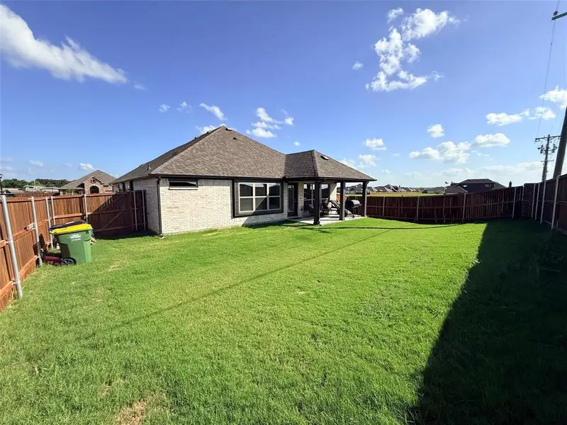 Expansive backyard featuring a covered patio, privacy fencing, and a manicured lawn Expansive backyard featuring a covered patio, privacy fencing, and a manicured lawn